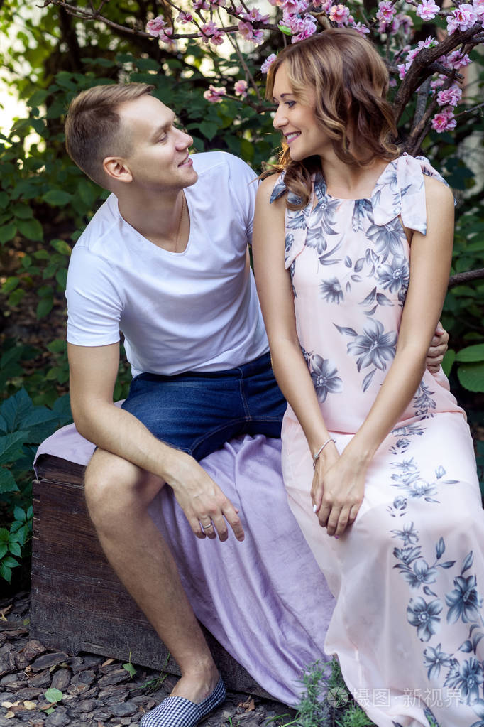 相爱的情侣坐在春天公园的木凳上看着对方, 爱的概念