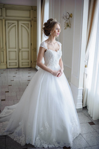 美丽的新娘在一个豪华的白色房间与一个大吊灯的婚纱礼服