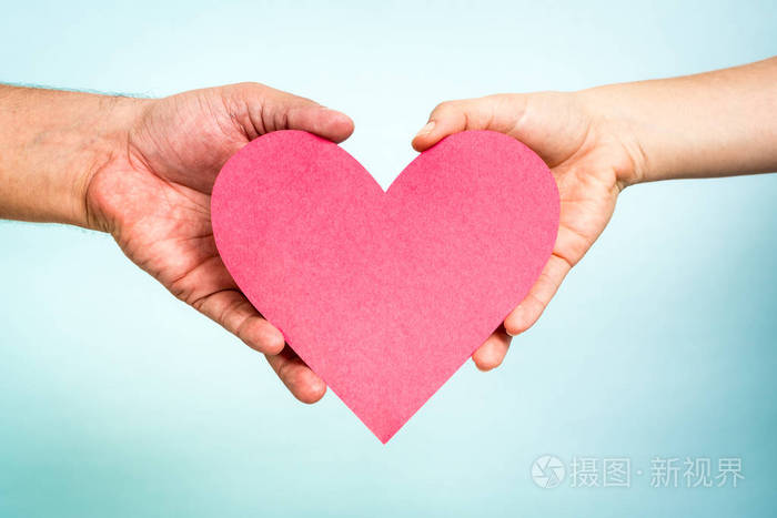 两只手捧着红纸爱心形在蓝色背景上