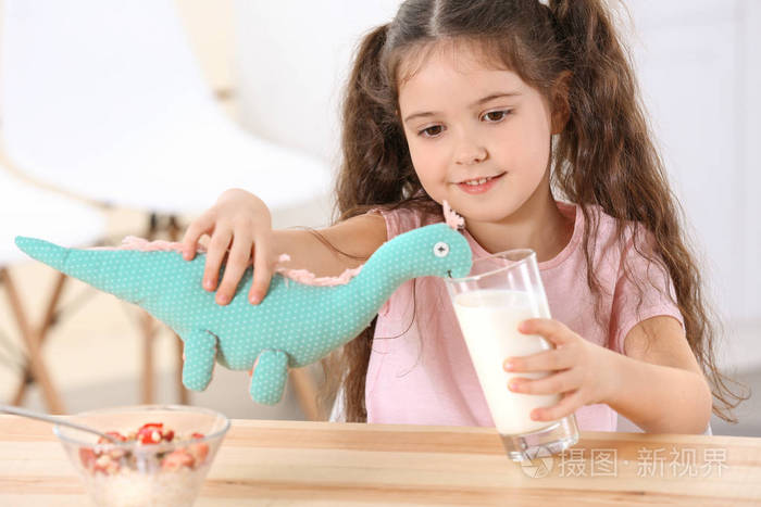 可爱的小女孩在餐桌上玩玩具恐龙
