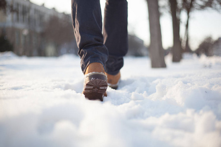 穿着红鞋和灰色牛仔裤的男人在雪地上漫步