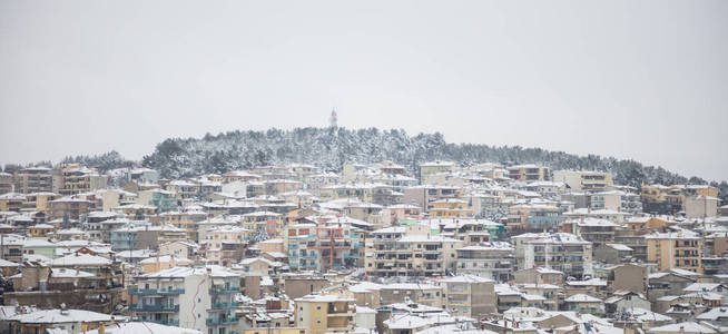 Kozani, 希腊。传统的雪镇和朦胧的天空背景。全景图