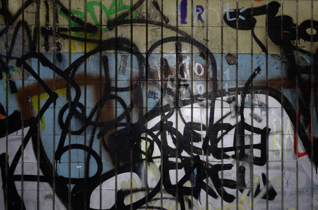 在地铁隧道的旧瓷砖上, 一幅涂鸦图画和一组标签应用到墙上。街头艺术与破坏的概念