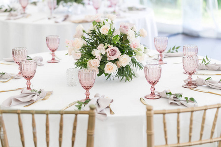 漂亮的餐桌上设置长满鲜花和陶器聚会 婚宴或其他节日活动。玻璃器皿和照顾的事件晚餐餐具