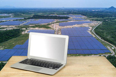 与太阳能农场的木桌上的笔记本电脑照片