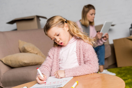 带毡尖笔的儿童绘图妈妈在沙发上使用数字平板电脑