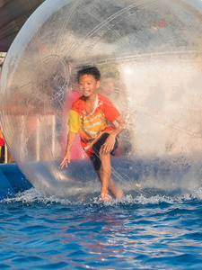 年轻的亚洲男孩在一个漂浮的水球里面玩耍