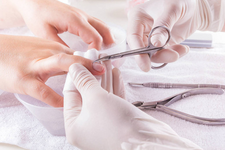 一个女人使用角质层推给修一下指甲指甲的特写镜头照片