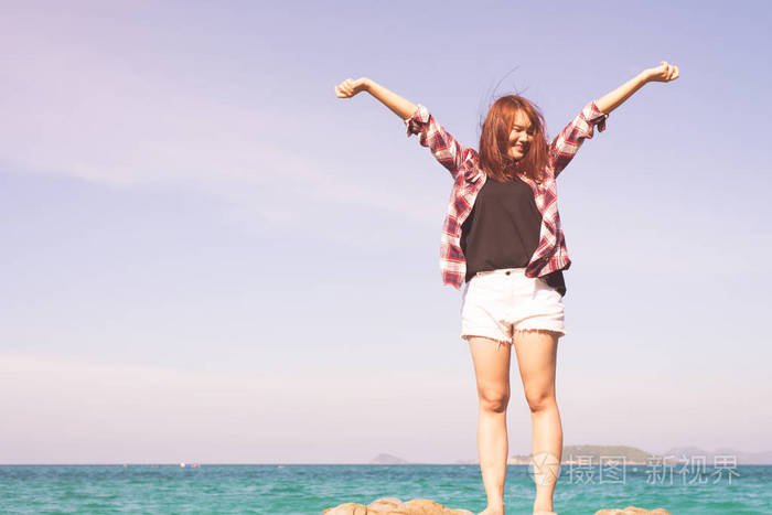 女人在海滩享受夏天张开双臂与头发在风中的自由水海边放松.