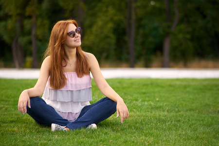 微笑的女士坐在绿色的草坪上