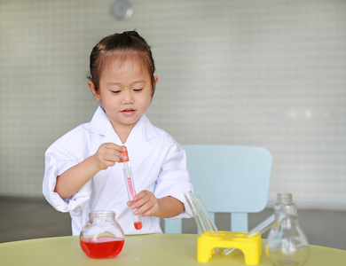 亚洲孩子在科学家一致的藏品试管与液体科学家化学和科学教育概念