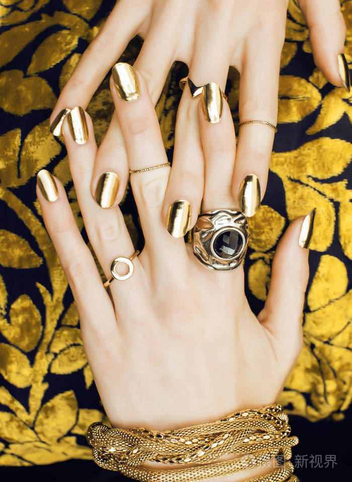 女人手与金色修指甲很多珠宝在华丽的礼服 c