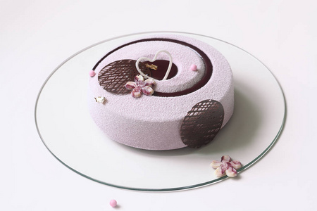 当代蓝莓紫慕斯蛋糕覆盖天鹅绒喷雾和装饰的巧克力元素, 在白色的背景