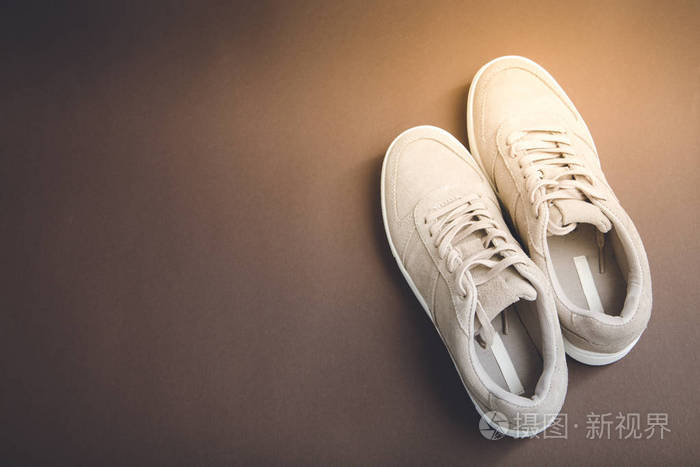 棕色背景的粉彩米色运动鞋.平躺, 最小 b