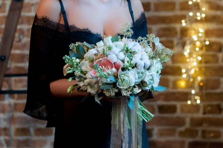 在黑色的睡衣站在阁楼背景与花环新娘和举行婚礼花束