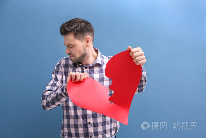 年轻人撕纸心脏一半在颜色背景.关系问题