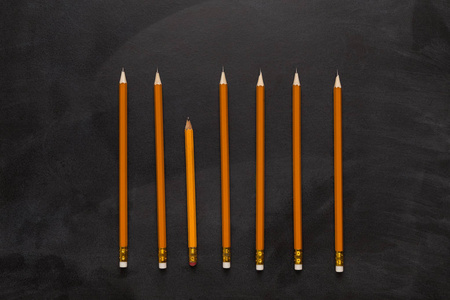 一个旧的和大量的新铅笔在黑色背景照片