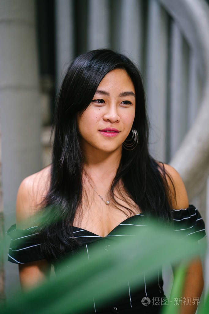 一位年轻的中国女律师 (新加坡人) 的肖像, 站在她办公室的墙边, 里面