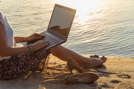 女士与一台笔记本电脑在海滩上的日落