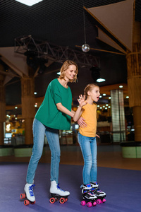 微笑的母亲和小女儿在溜冰场溜冰