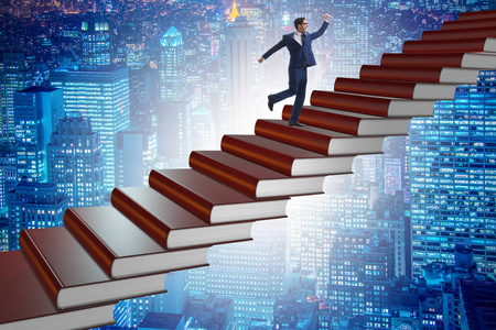 攀登教育书籍阶梯的商人学生照片