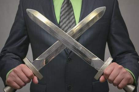 商人手持一把交叉的玩具剑武器.人寿保险或金融保险代理.