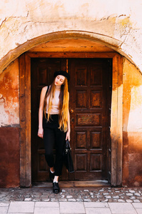 一个美丽苗条的女孩站在一个老房子的门附近