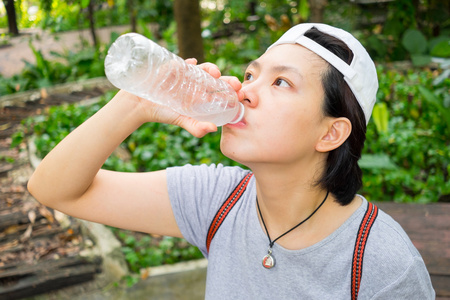 在公园里的亚洲女人喝水