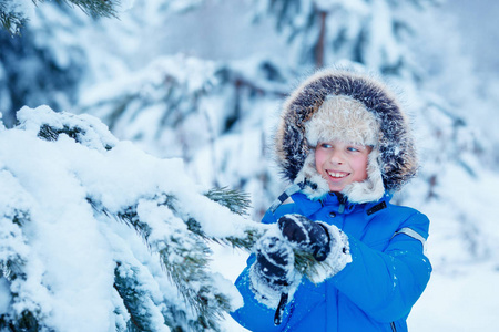 可爱的小男孩,穿着暖和的衣服,在冬天森林上玩照片