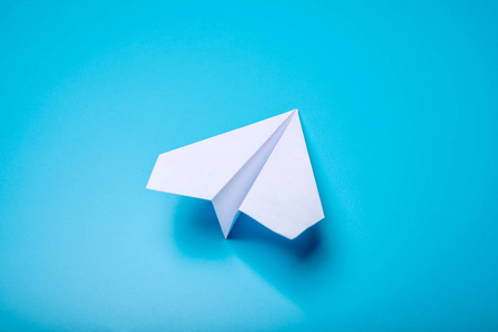 白皮书折纸飞机位于柔和的蓝色背景