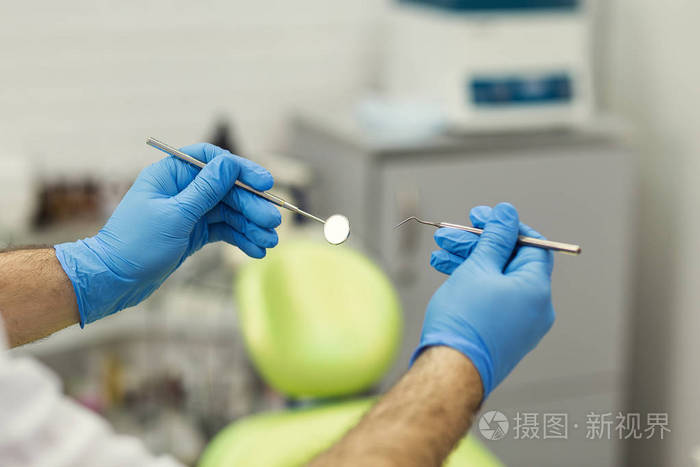 男性牙医用工具在医疗办公室背景.医疗保健,专业,口腔医学理念