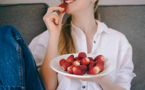 年轻妇女吃健康的食物 srawberries 在家, 健康的