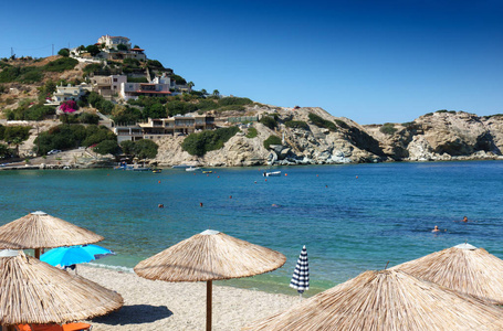 在海滩的遮阳伞在山, 伊拉克利翁, 希腊的海岸房子