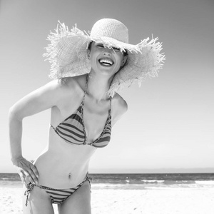 蓝海, 白沙乐园。微笑的现代妇女在比基尼和海滩草帽在海岸