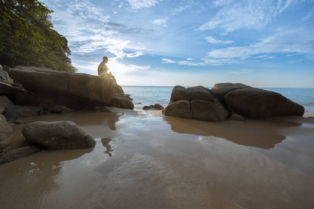 泰国金沙岛坐在海滩上岩石上的男人照片