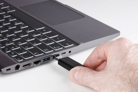 内存插槽银色笔记本电脑和男性手持 usb 闪存盘并插入插槽-白色背景