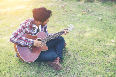 年轻的时髦的人在公园里练习吉他, 快乐和享受 p。