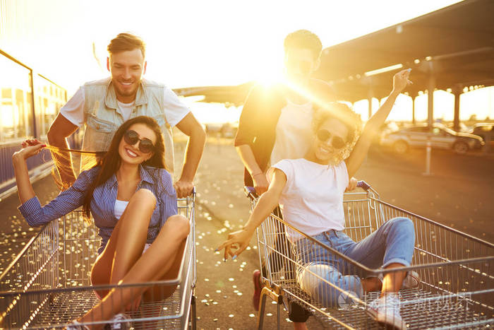 一群快乐的年轻人在购物手推车上玩得开心.