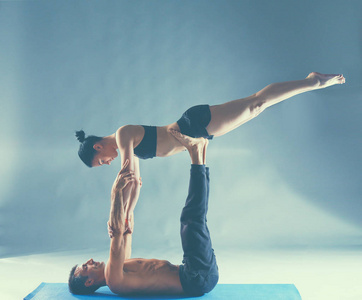 年轻夫妇一起练习杂技瑜伽工作室在垫子上
