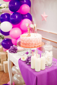 一个可爱的粉红色和紫色的糖果酒吧在她的第一岁的小公主。美丽的装饰儿童党与气球鲜花和糖果