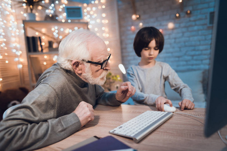 祖父和孙子在桌上玩电脑游戏