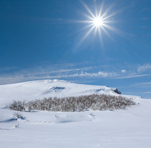 白色的大雪山丘下闪闪发光的太阳