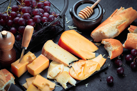黑色石板板与各种奶酪, 装饰葡萄, 面包和蜂蜜