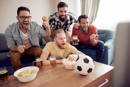 一群朋友足球爱好者观看足球比赛在电视和庆祝目标