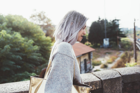 腰部的年轻白种人紫色灰色头发妇女在城市户外看着, 微笑着