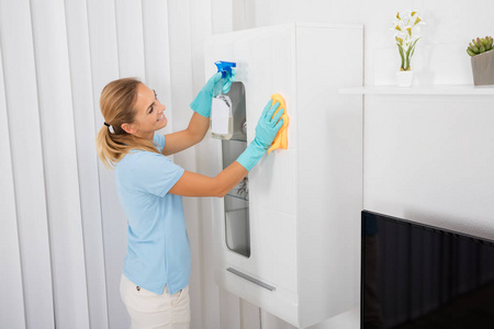 家具抛光液年轻的清洁剂擦拭表擦桌子的黄色橡胶手套的女人手用抹布上