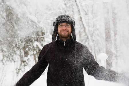 男子在毛皮冬季帽子与耳襟翼微笑的肖像。极端在森林里