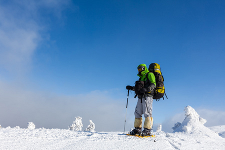 背包客男人在冬天山走在阳光灿烂的日子