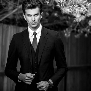 黑色白色室外肖像的优雅英俊的男人在木栅栏附近的经典西装照片