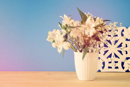 在木桌和蓝色背景的花瓶里的白色花朵的夏天花束